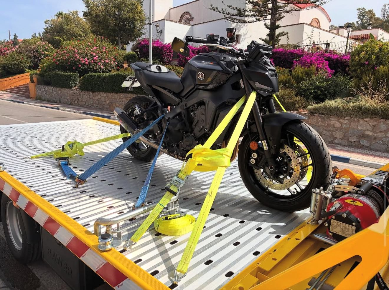 Grúa para motos en Marbella de Grúas Sánchez con moto sujeta sobre la plataforma en la Costa del Sol